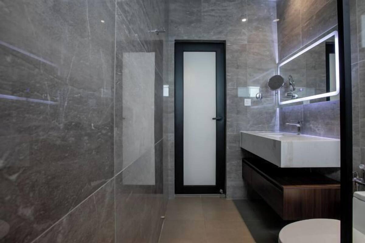 Une salle de bain moderne avec une douche à parois de verre, un lavabo blanc avec un miroir et un meuble-lavabo en bois foncé.