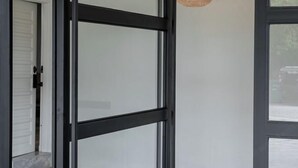 Een modern interieur met een glazen deur, een witte muur en een plafondlamp met een structuur.