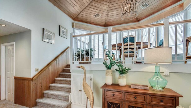A staircase with a wooden handrail leading to a landing with a view of a balcony. - Tappan, Ships Watch Community in Duck, NC (Duck)