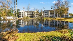 Un bâtiment doté de nombreuses fenêtres, dont le reflet se mire dans un étang.