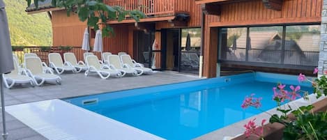 A swimming pool with lounge chairs and a wooden building with balconies.