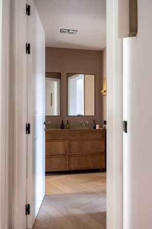 A modern bathroom with a wooden vanity, a large mirror, and a light fixture above the mirror.