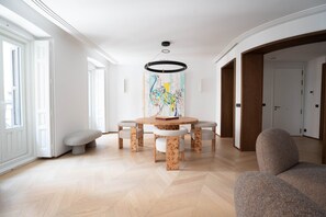 A modern dining area with a round table, benches, and a hanging light fixture.