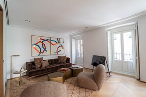 A modern living room with a brown sofa, a coffee table, and a large abstract painting on the wall.
