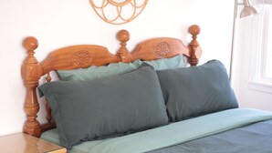 A bedroom with a wooden bed, a bedside table, a lamp, and a wall mirror.