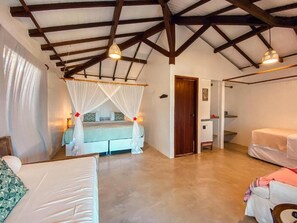 A bedroom with a bed under a canopy, a wooden ceiling, and a door leading to another room. - Pousada San Antônio Praia  (Porto Seguro)