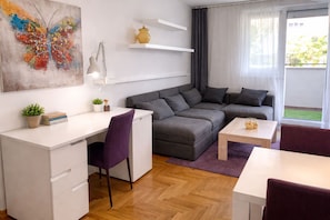 A modern living room with a desk, a sofa, a coffee table, and a painting on the wall.