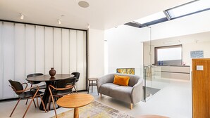 Ein modernes Wohnzimmer mit Essbereich, einer Couch und einer Küche im Hintergrund.