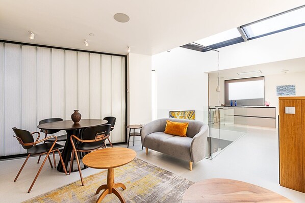 Ein modernes Wohnzimmer mit Essbereich, einer Couch und einer Küche im Hintergrund.