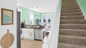 A kitchen with white cabinets, a stainless steel dishwasher, and a wooden cutting board on the counter. - Ocean View Oasis for 8-Food Trucks @ Your Doorstep (Mexico Beach)