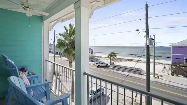 A balcony with chairs, a view of the beach, and a white truck parked on the street. - Ocean View Oasis for 8-Food Trucks @ Your Doorstep (Mexico Beach)