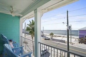 Un balcone con sedie, vista sulla spiaggia e un furgone bianco parcheggiato in strada.