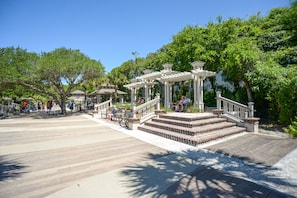 A wooden boardwalk leading to a gazebo with steps and railings, surrounded by trees.