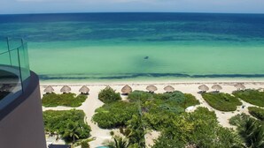 Une vue sur la plage, avec un ciel dégagé, une plage de sable et un espace piscine agrémenté de parasols.