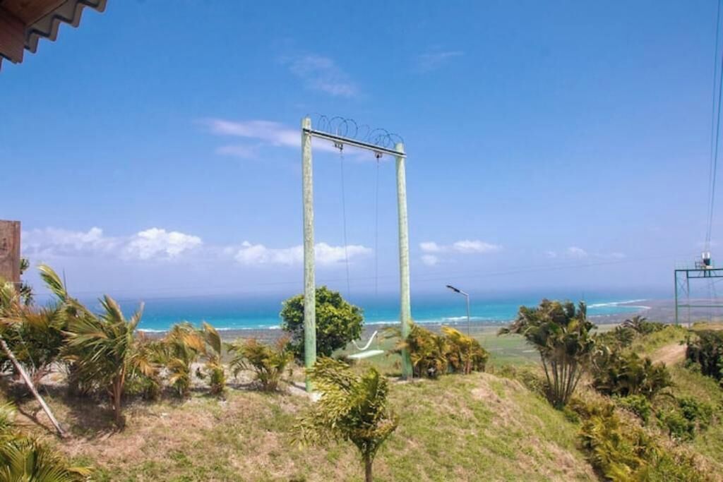 A view of a coastal area with a swing set, palm trees, and a clear blue sky.