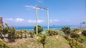 Una vista di una zona costiera con altalene, palme e cielo azzurro intenso.