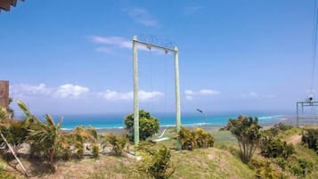 A view of a coastal area with a swing set, palm trees, and a clear blue sky.