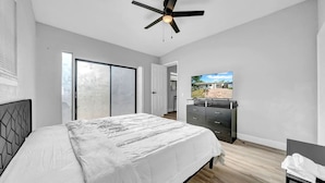 A bedroom with a bed, a dresser, a ceiling fan, and a TV. - Modern Retreat | Under 15min/Downtown Orlando (Orlando)