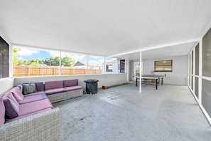 Un espacio de patio cubierto con un sofá, una mesa y un cubo de basura.