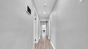 A narrow hallway with light grey walls and wooden flooring. - Modern Retreat | Under 15min/Downtown Orlando (Orlando)