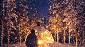 En person som går mot ett snötäckt tält i en skog under natten.