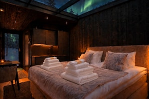 Ein gemütliches Schlafzimmer mit einem großen Bett, einem Holz-Kopfteil und Blick auf den Nachthimmel.