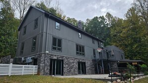 A modern two-story house with a stone foundation, large windows, and a basketball hoop.