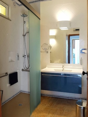 Un baño con ducha, lavabo y espejo.