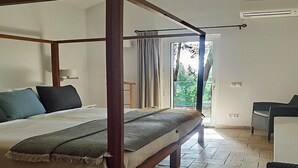 A bedroom with a four-poster bed, a wooden floor, a small table, and a chair. - Apart-hotel Quinta Das Eirinhas-jardim De Bonsai (Tavira)