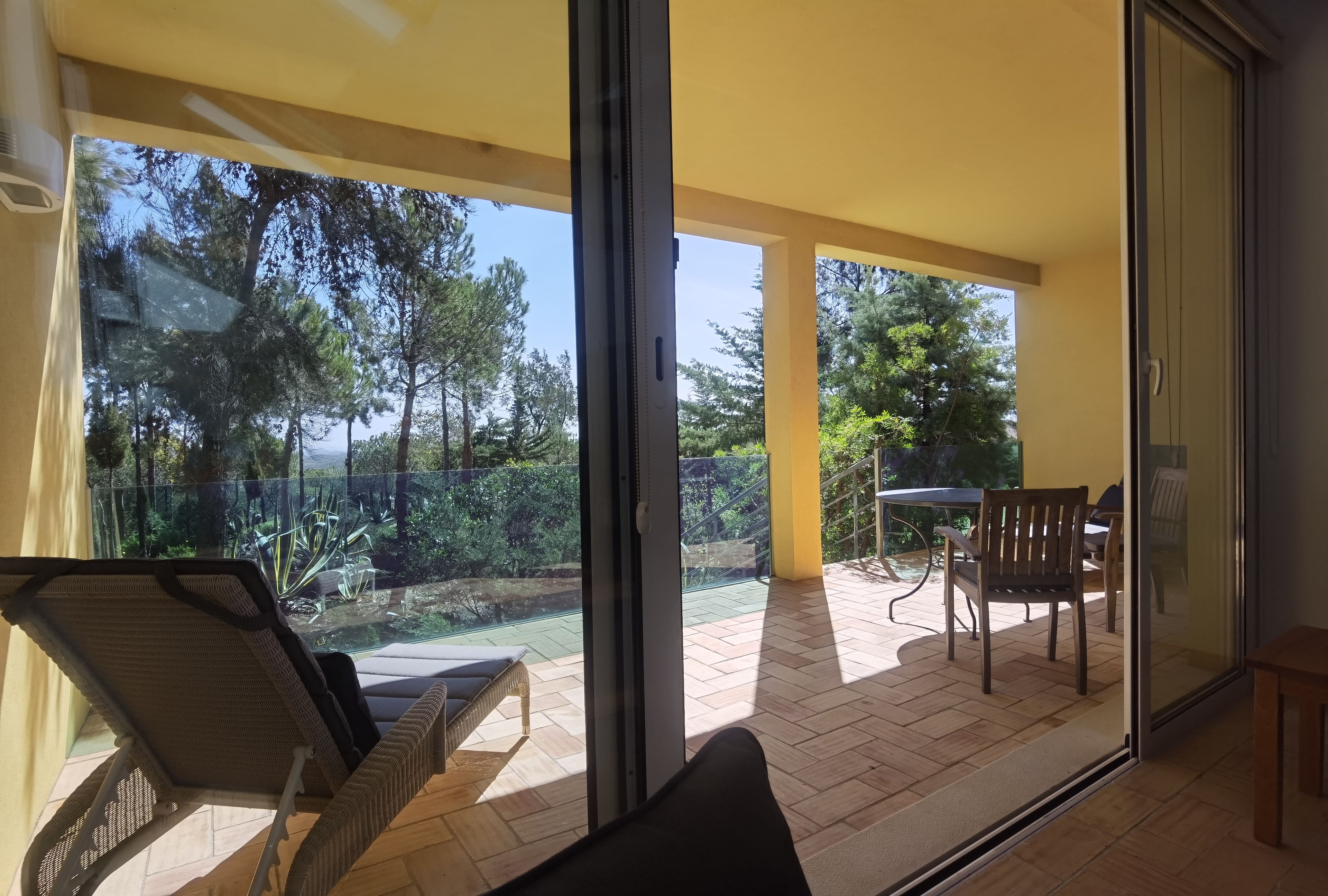 Ein Balkon mit Glastür, einem Korbstuhl und einem Tisch mit Stühlen.