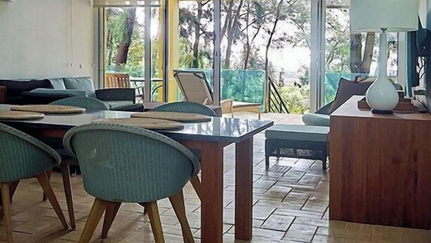 A modern living room with a high ceiling, skylights, and large windows offering a view of the outdoors. - Apart-hotel Quinta Das Eirinhas-jardim De Bonsai (Tavira)