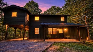A two-story wooden cabin with a covered porch, a garage, and a fenced driveway. - Private Heated Pool (Apr–Nov), Game Loft & Grill | Family Retreat Sleeps 11 (Sevierville)