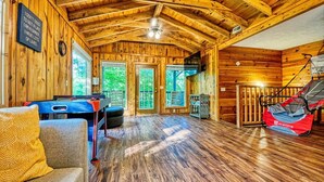 A wooden cabin interior with a pool table, a sofa, and a trampoline. - Private Heated Pool (Apr–Nov), Game Loft & Grill | Family Retreat Sleeps 11 (Sevierville)