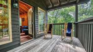 A wooden deck with a covered porch, a wooden chair, and a bench. - Private Heated Pool (Apr–Nov), Game Loft & Grill | Family Retreat Sleeps 11 (Sevierville)