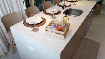 Una cocina moderna con una isla central, un fregadero y una zona de comedor con sillas y platos.