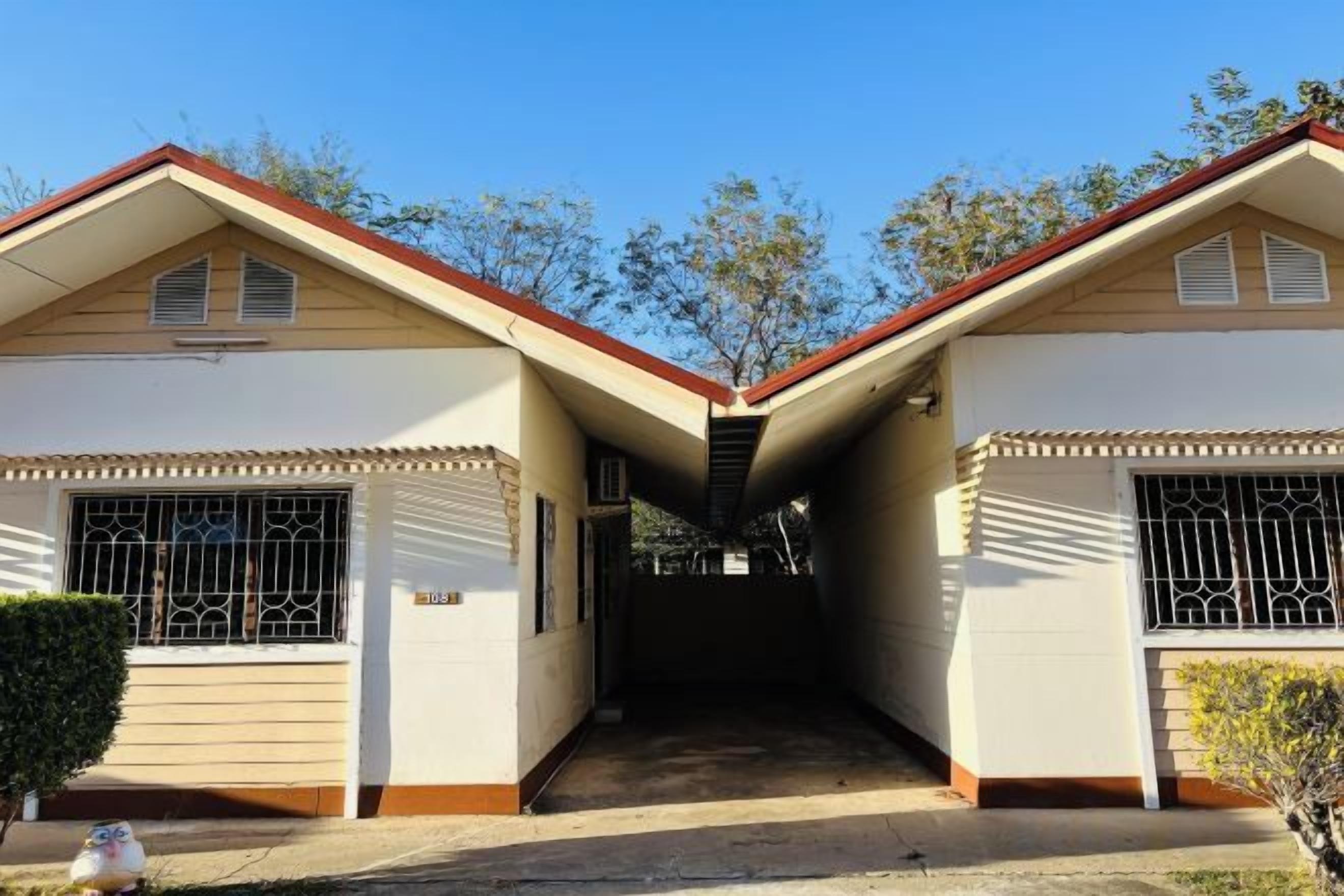 Une maison à deux étages avec un accès au garage, un petit jardin devant et un ciel dégagé.