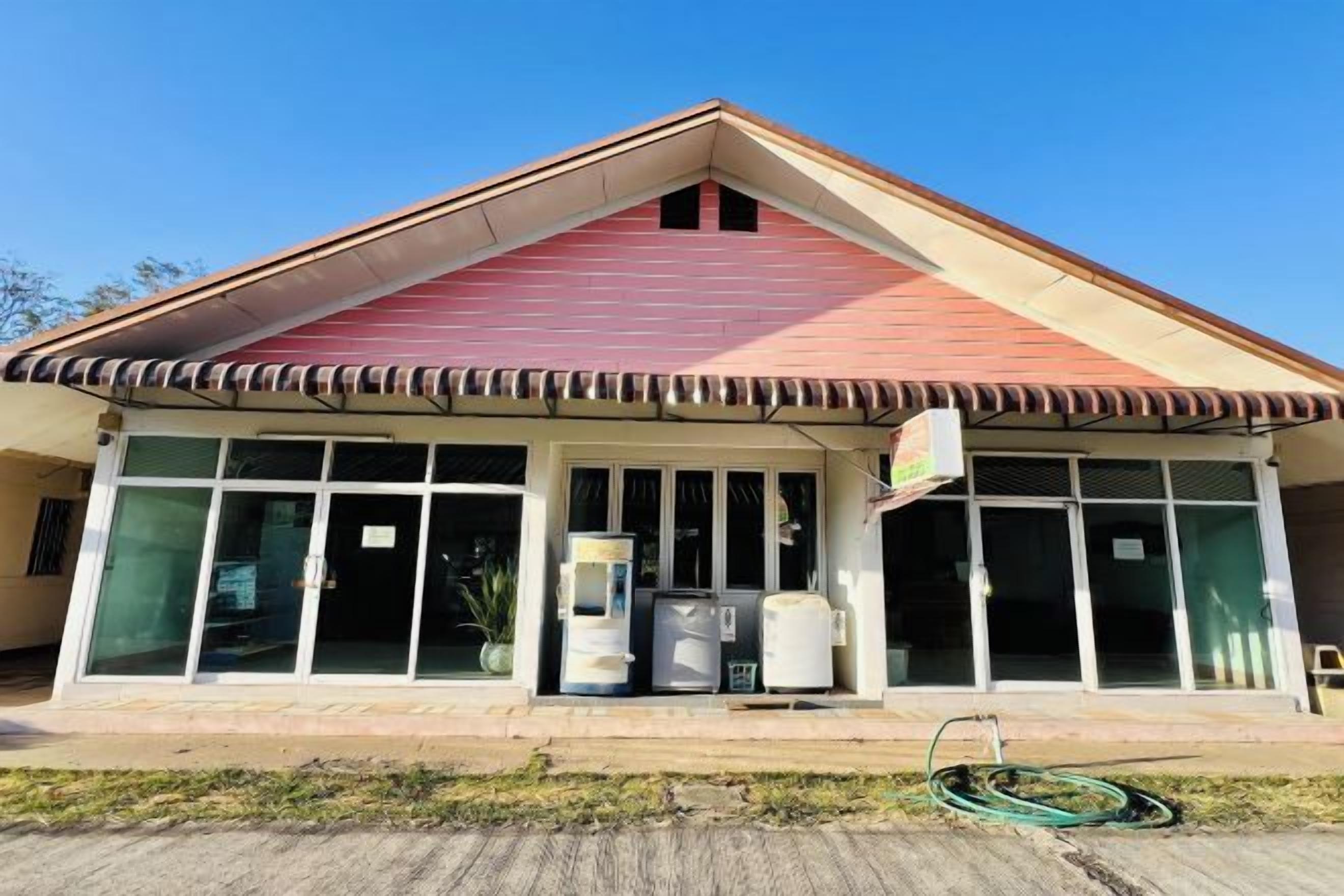 A building with a red roof, large windows, and a covered entrance area.