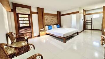 A hotel room with a bed, a wooden headboard, a nightstand, a wicker chair, and a view of the outside.