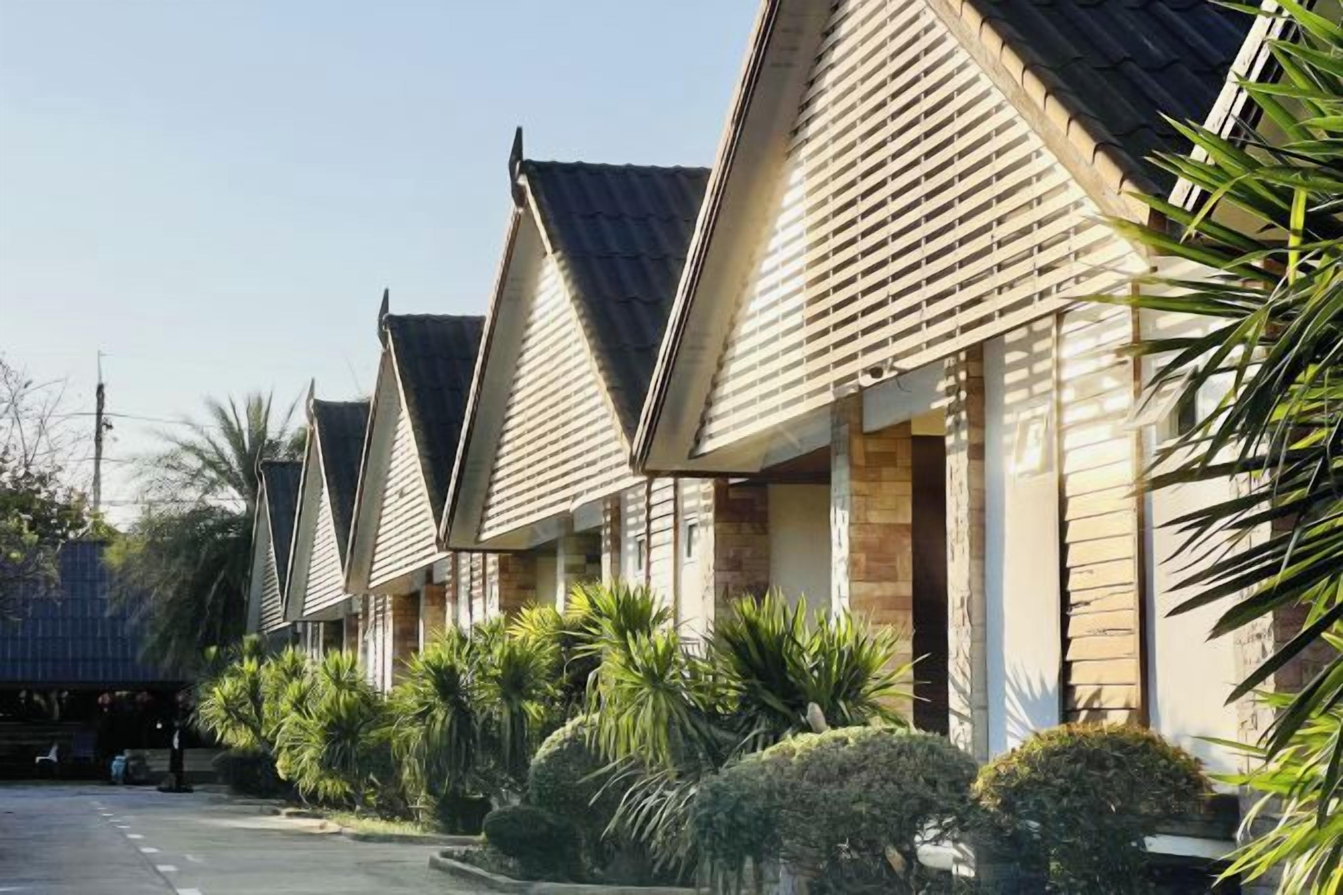 A row of motel-style buildings with pitched roofs and brick exteriors, surrounded by well-maintained landscaping.