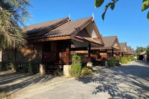 A row of traditional wooden houses with sloped roofs, a paved pathway, and a clear sky. - Ruentara Resort & Villa (Buri Ram)