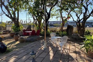 An outdoor patio area with stone flooring, outdoor furniture, and potted plants. - Ruentara Resort & Villa (Buri Ram)