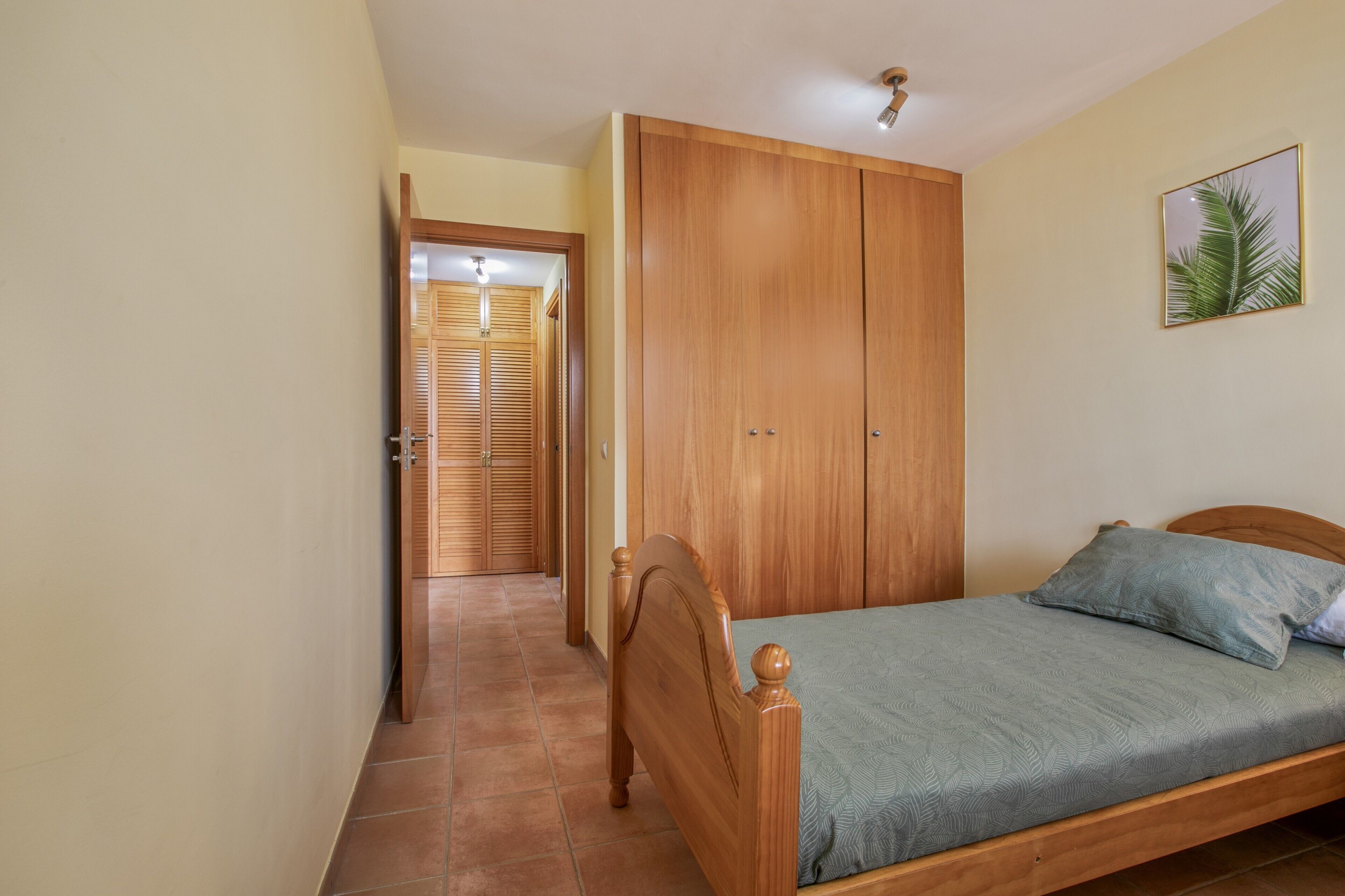 Une chambre à coucher avec un lit en bois, une armoire et une porte donnant sur une autre pièce.