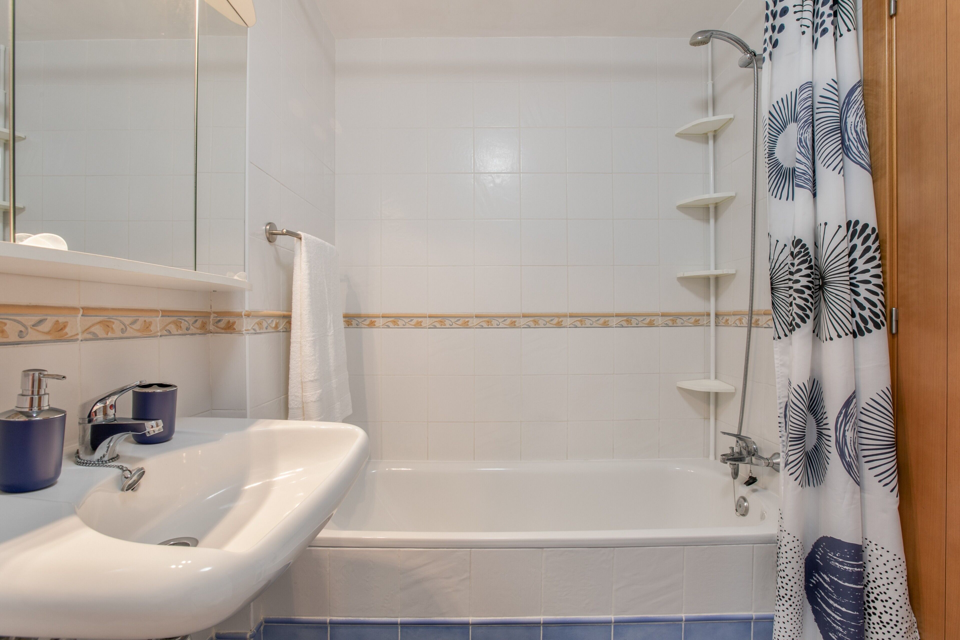 A bathroom with a sink, mirror, and bathtub.