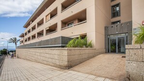 A multi-story building with a flat facade, a ground-level entrance, and a visible balcony on the second floor. - Holiday Apartment 'Palm Serenity' with Shared Pool, Wi-Fi and Air Conditioning (Santa Cruz de Tenerife)
