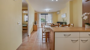 A kitchen with a dining area, a clock on the wall, and a potted plant. - Holiday Apartment 'Palm Serenity' with Shared Pool, Wi-Fi and Air Conditioning (Santa Cruz de Tenerife)