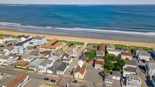 A coastal residential area with houses, a beach, and a clear view of the ocean.