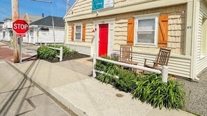A small, single-story building with a red door and a sign above it.