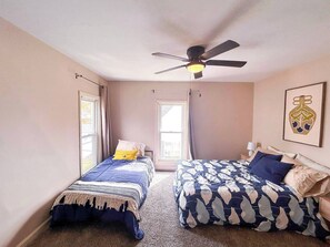 A bedroom with two beds, a ceiling fan, and a window.