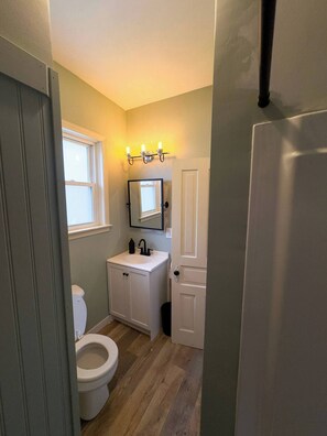 A compact bathroom with a white sink, a mirror, and a toilet.
