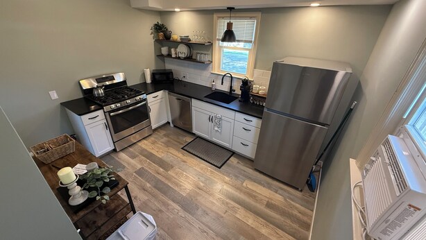 Una cucina moderna con elettrodomestici in acciaio inossidabile, mobili bianchi e pavimento in legno.